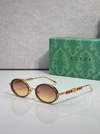 Gucci round sunglasses with gold-tone frame and brown gradient lenses.