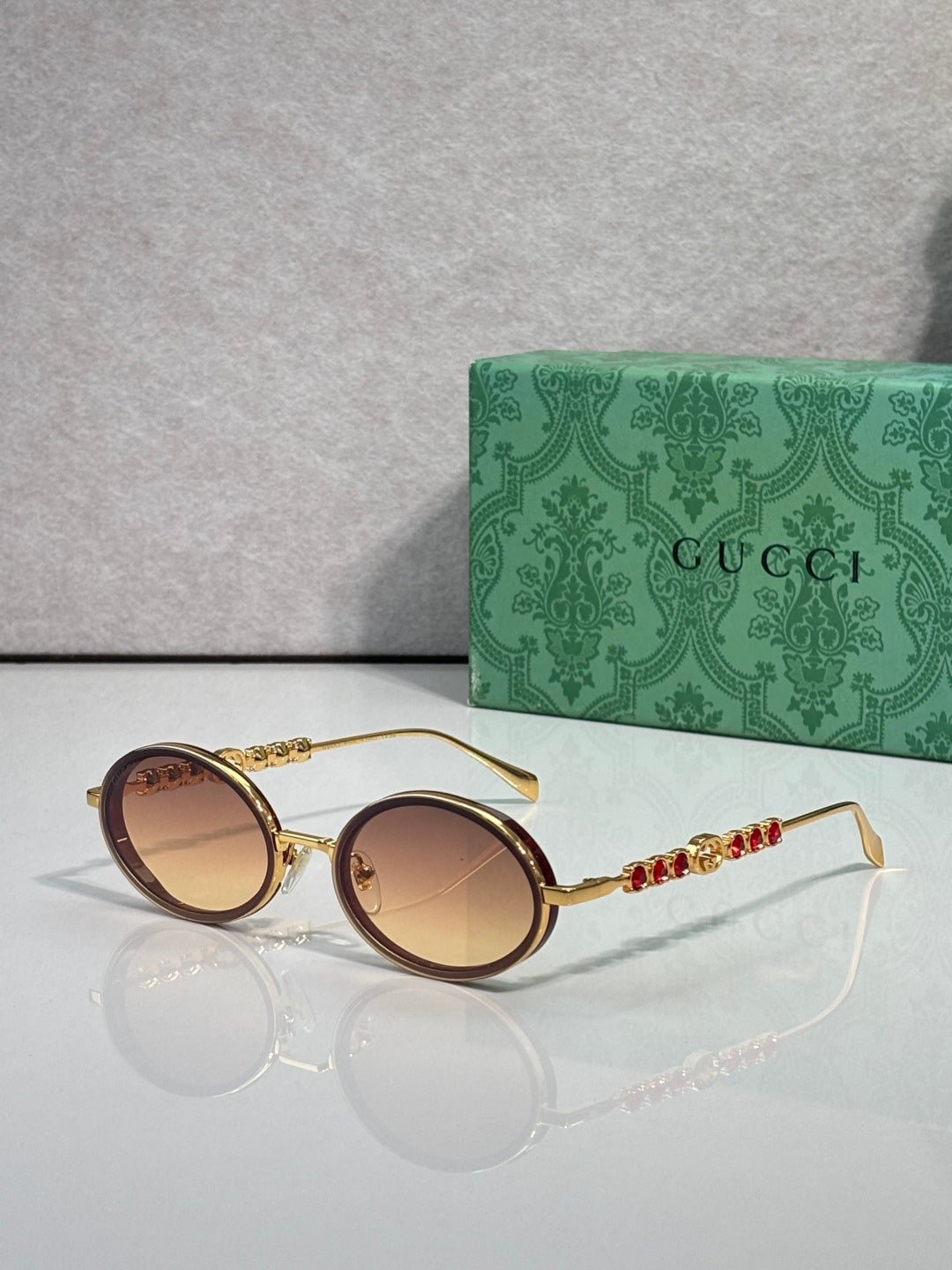 Gucci round sunglasses with gold-tone frame and brown gradient lenses.