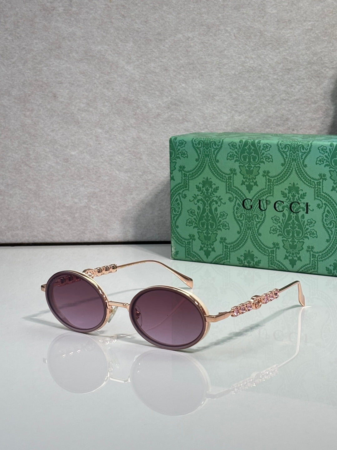 Gucci round sunglasses with gold-tone frame and purple gradient lenses.