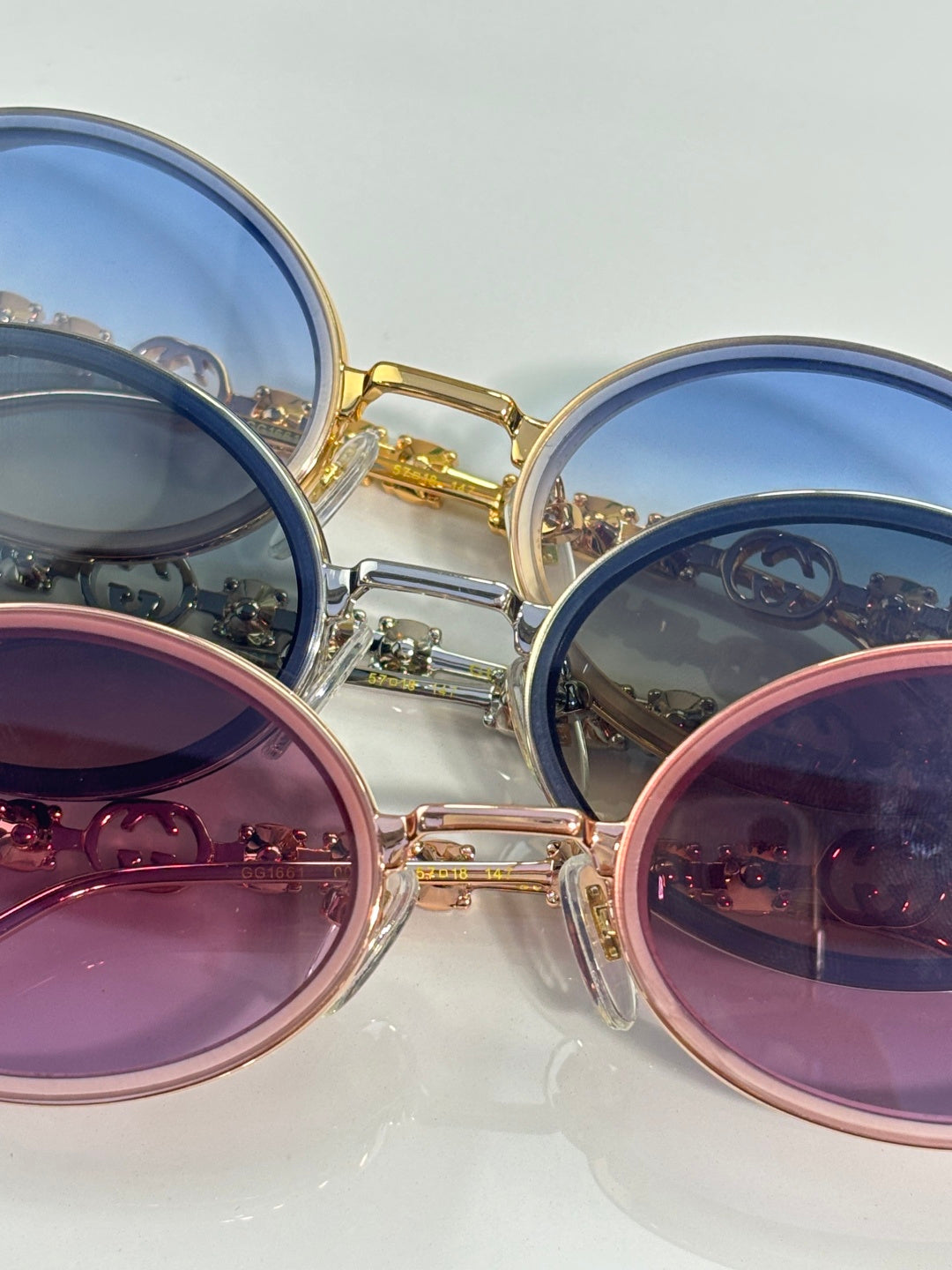 Gucci round sunglasses close-up with blue and pink lenses in gold and silver frames.