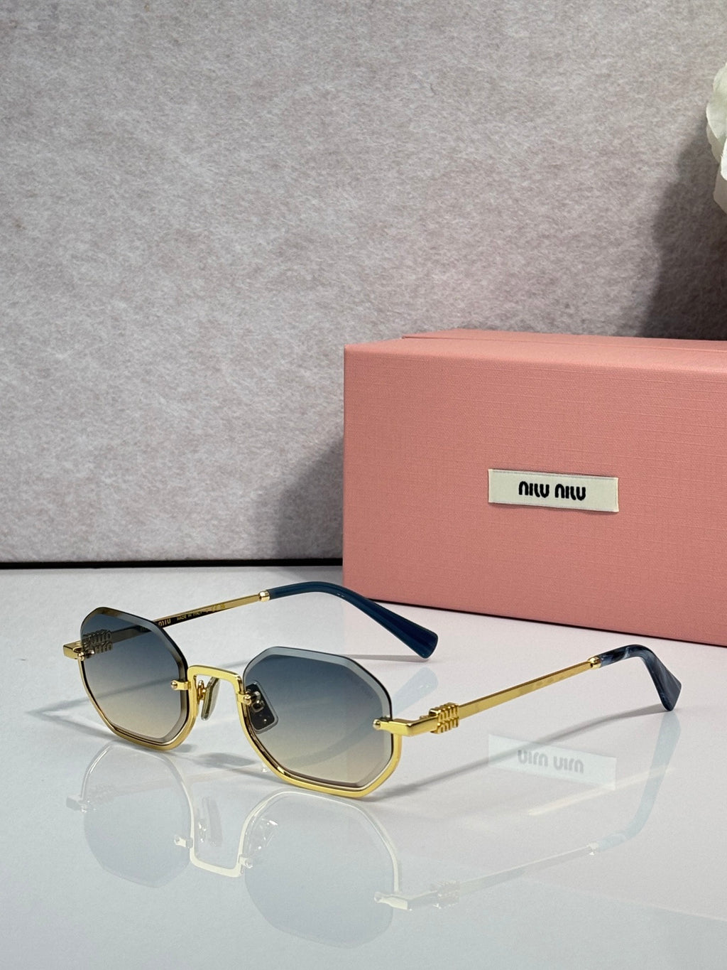MiuMiu sunglasses with gold frame, blue tinted lenses, rounded butterfly shape