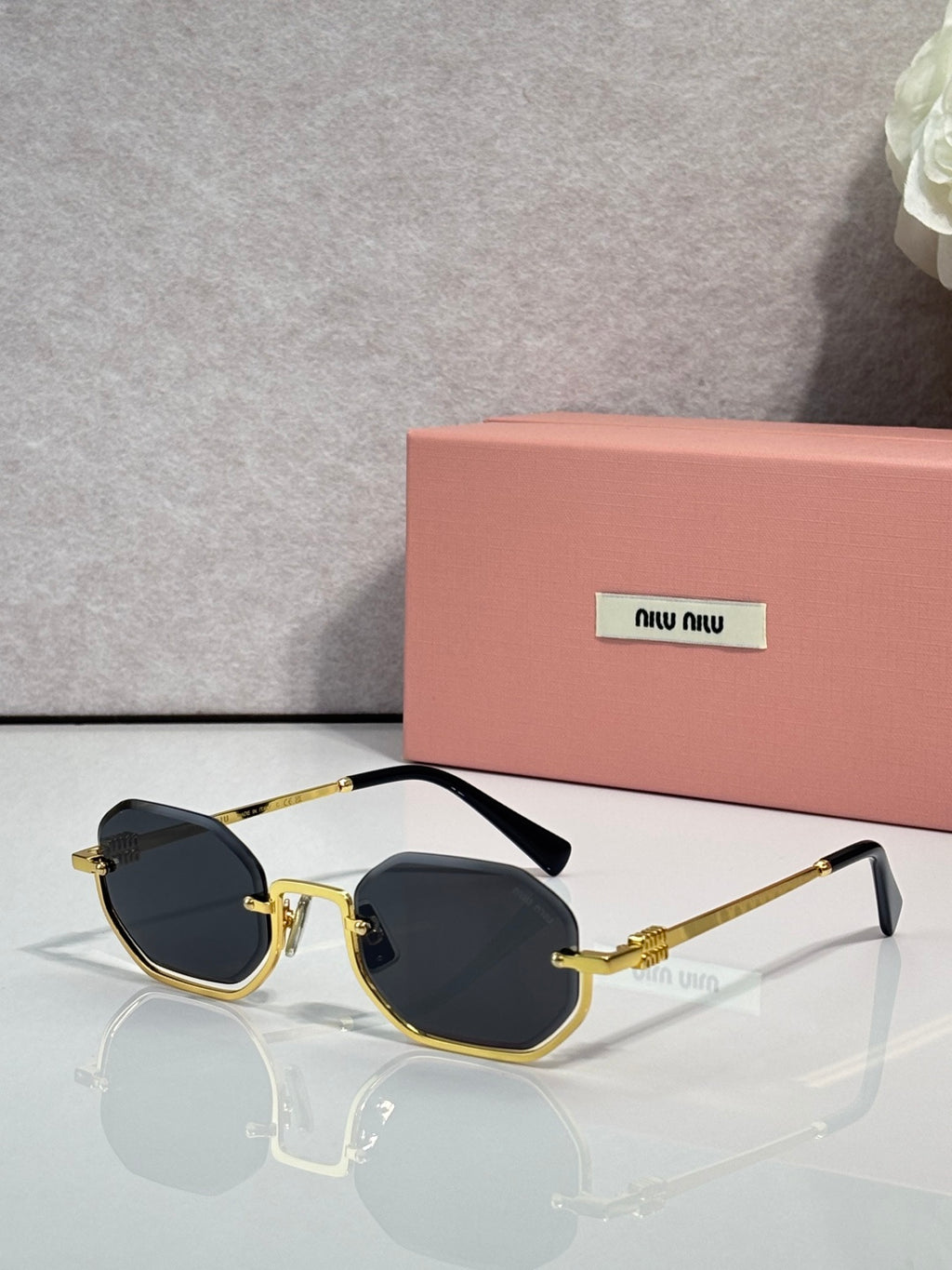 MiuMiu sunglasses with gold frame, black tinted lenses, rounded butterfly shape