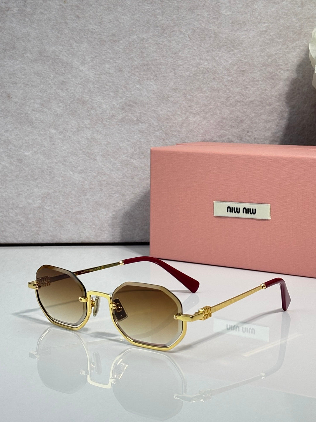 MiuMiu sunglasses with gold frame, light brown tinted lenses, rounded butterfly shape