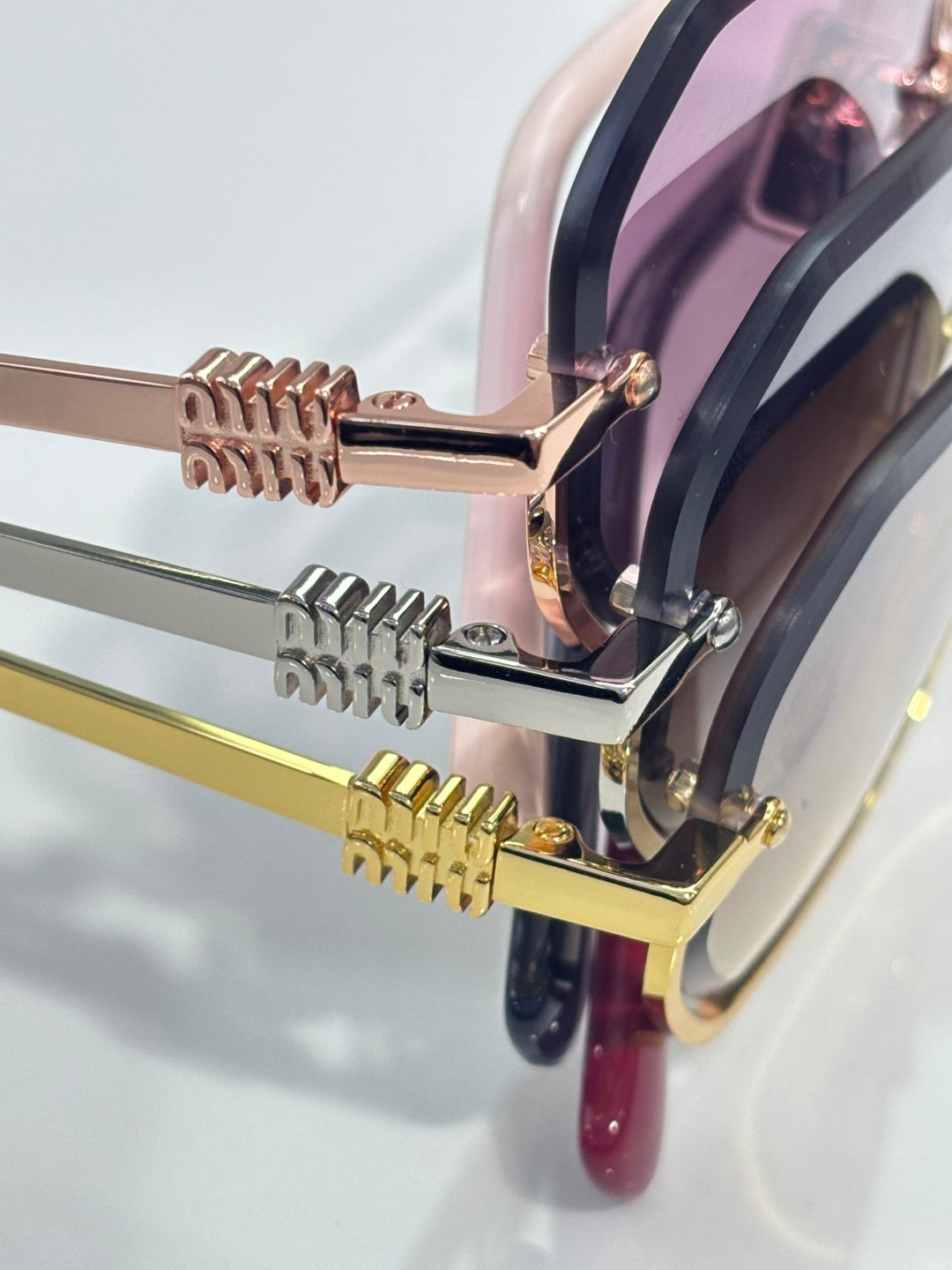 MiuMiu sunglasses hardware closeup with gold arms and hinged metal details