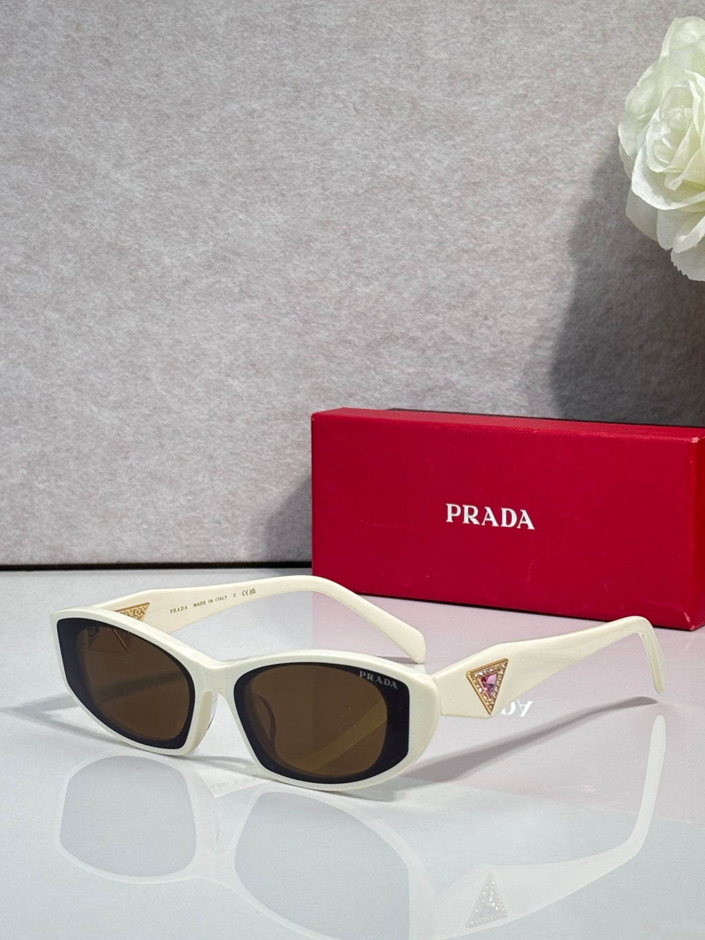 White cat-eye sunglasses with brown lenses and gold triangular temple accents
