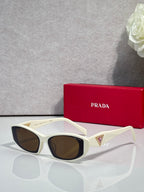 White cat-eye sunglasses with brown lenses and gold triangular temple accents