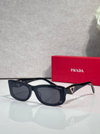 Prada sunglasses with black frames and dark lenses, triangular logo on side arm.