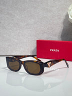 Prada sunglasses with tortoise-pattern frames and dark lenses, triangular logo on temple.