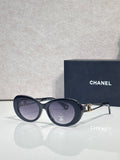 Dark blue round sunglasses with gold Chanel emblem and tinted lenses