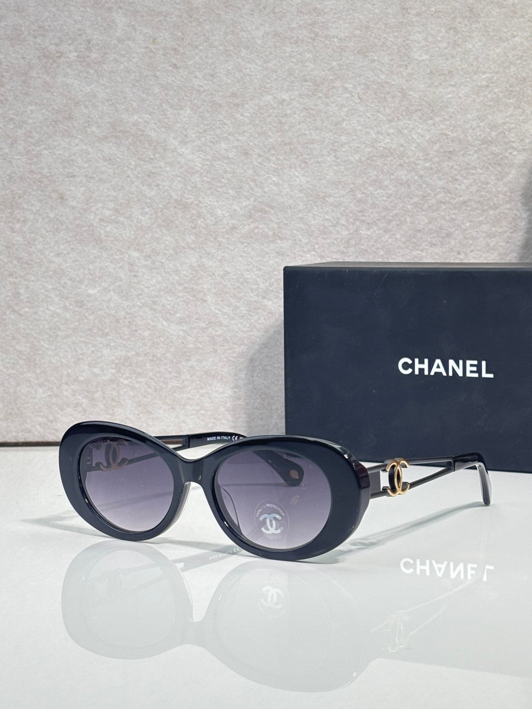 Dark blue round sunglasses with gold Chanel emblem and tinted lenses