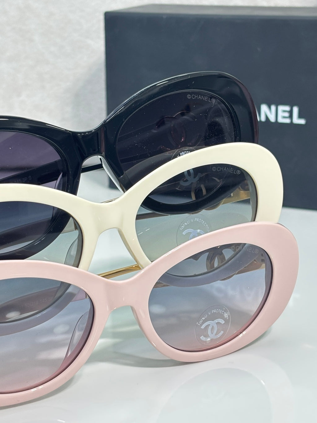 Stacked round sunglasses frames in navy, cream, and pink with tinted lenses
