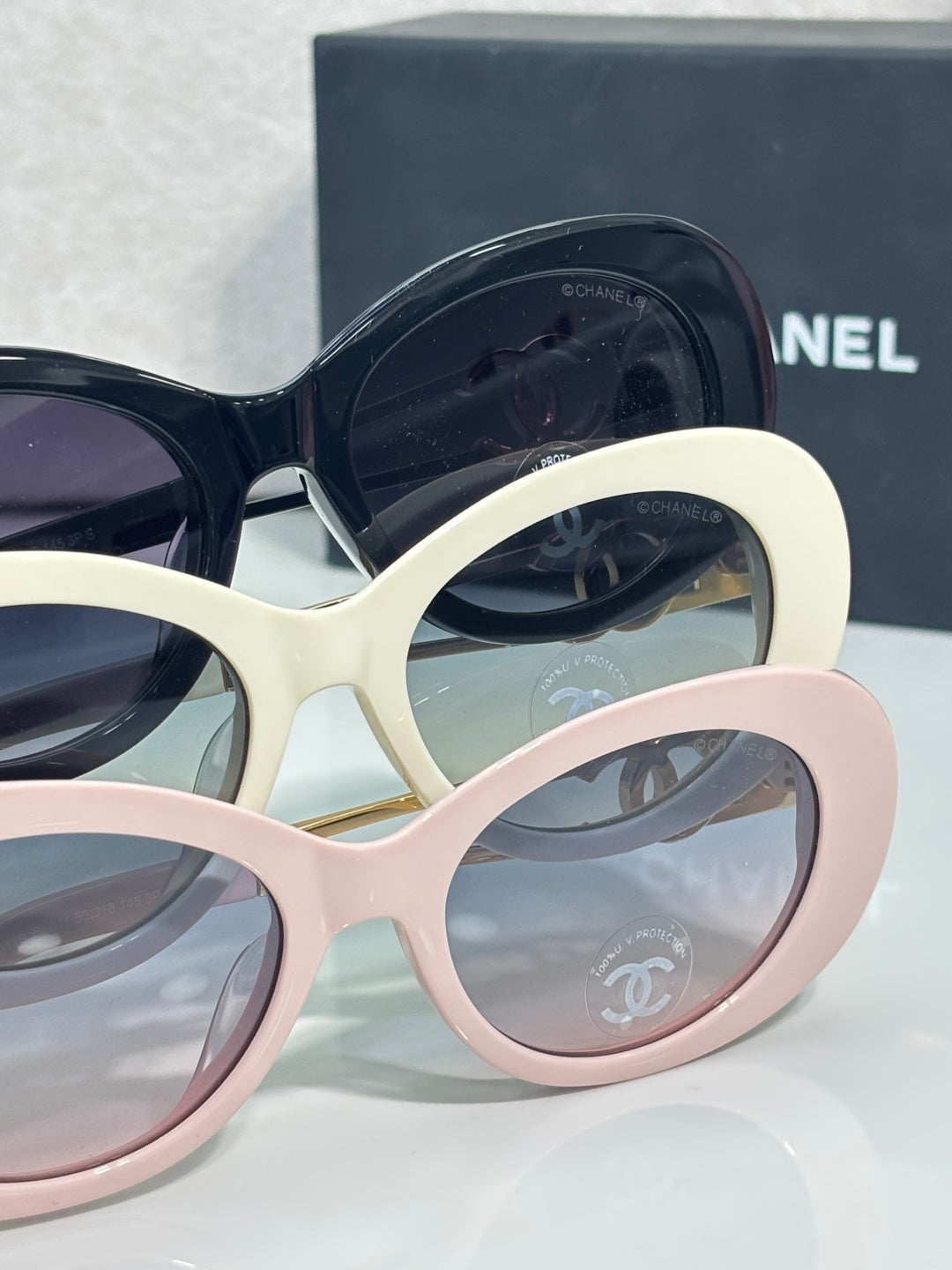 Stacked round sunglasses frames in navy, cream, and pink with tinted lenses
