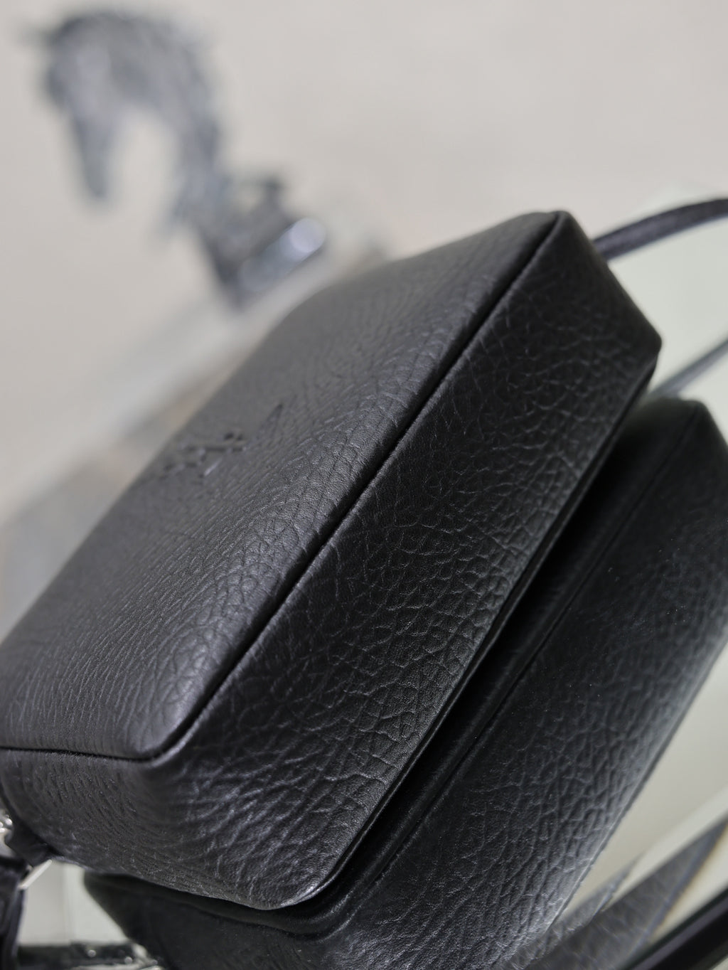 Front flap and spine seam detail on a black pebbled YSL leather crossbody bag.
