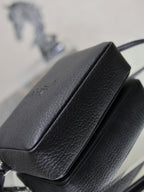 Front flap and spine seam detail on a black pebbled YSL leather crossbody bag.