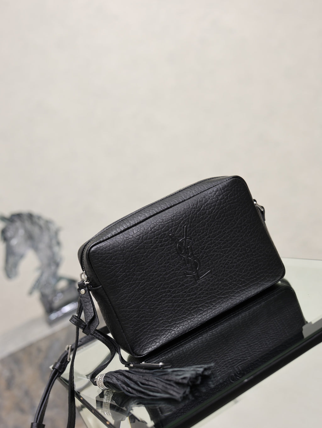 YSL leather crossbody bag in black pebbled finish with YSL logo on the flap.
