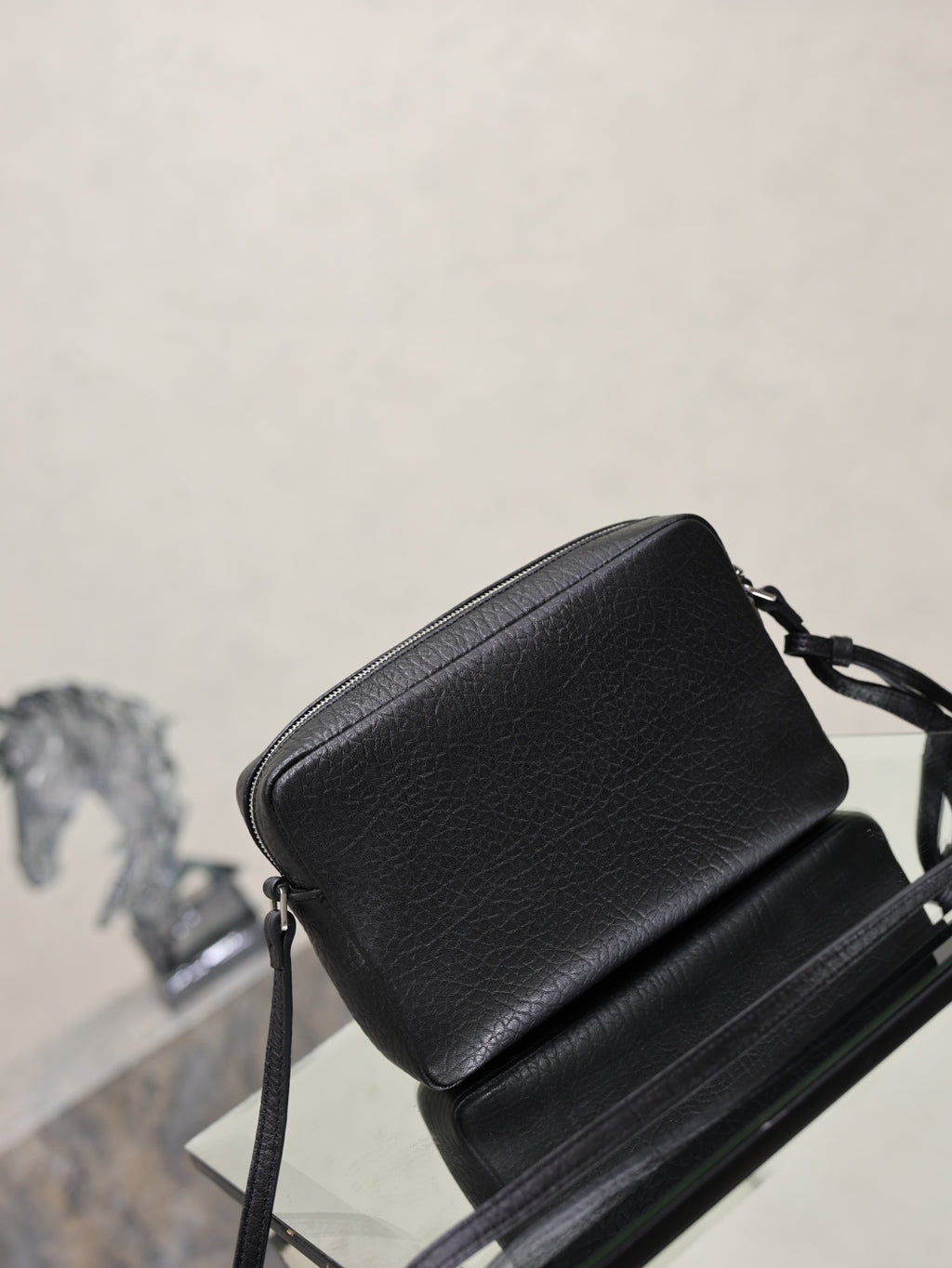 Black pebbled leather YSL crossbody bag with shoulder strap and compact rectangular shape.