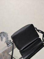 Black pebbled leather YSL crossbody bag with shoulder strap and compact rectangular shape.