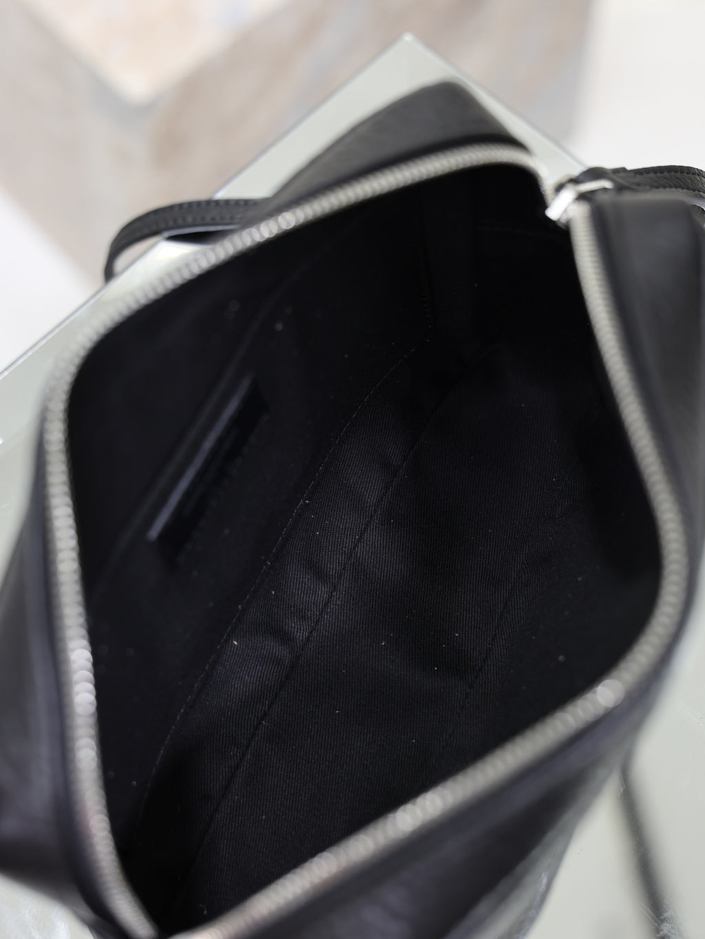 Open black-lined interior of a YSL leather crossbody bag with stitched side panels.