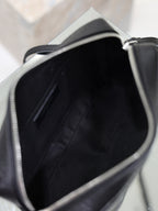 Open black-lined interior of a YSL leather crossbody bag with stitched side panels.