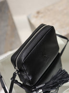 Black YSL zip-top crossbody bag with pebbled leather and tassel detail at the side.