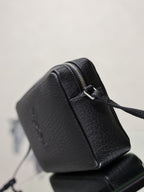 Black pebbled leather YSL crossbody bag with curved side and visible zip closure.