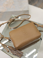 Tan leather YSL crossbody bag on display with embossed logo and tassel strap.