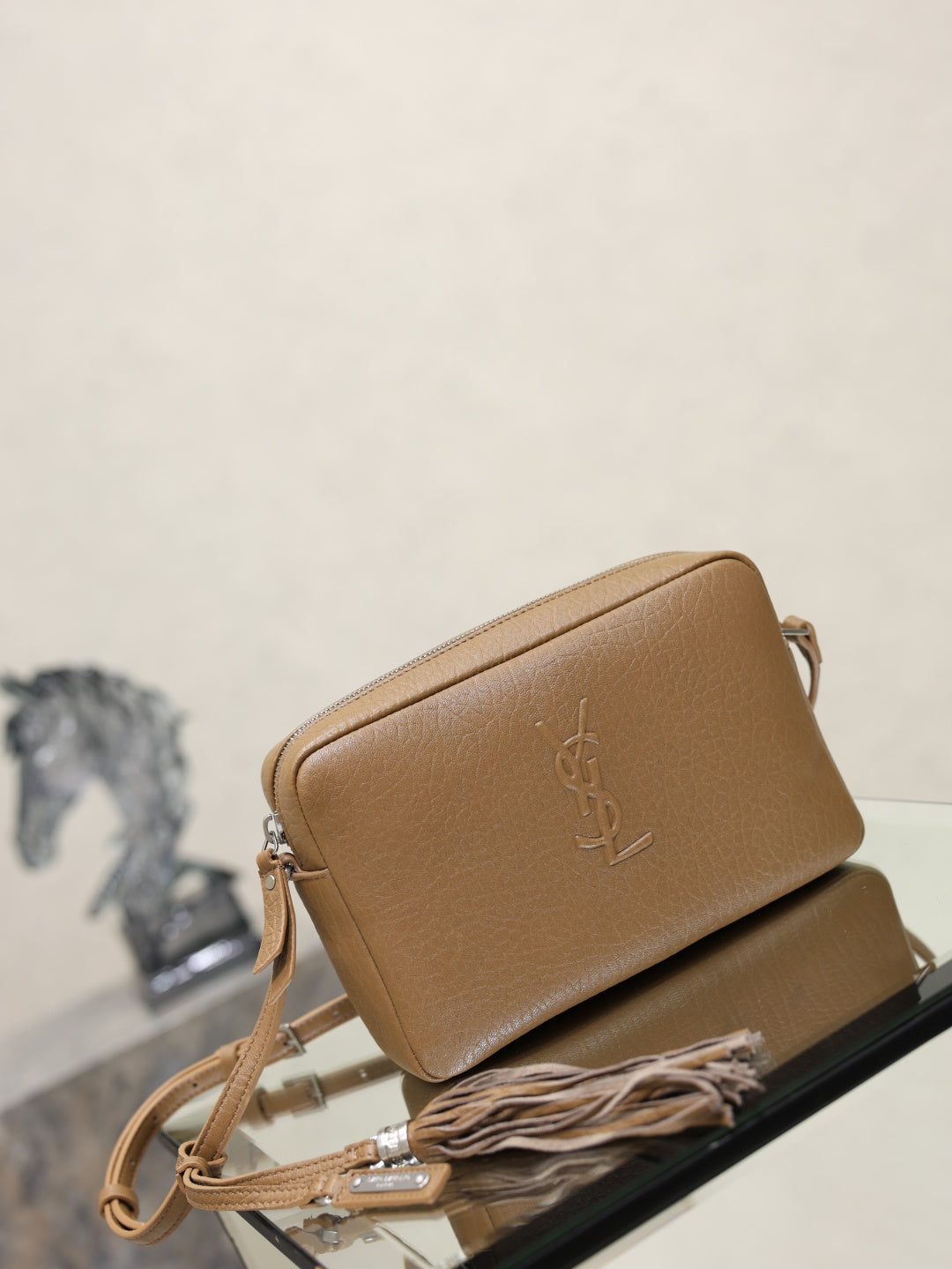 YSL leather crossbody bag in tan, angled view, with embossed YSL logo and zipper.