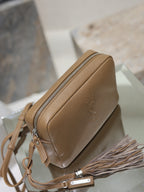 Tan YSL leather bag with top zipper, tassel detail, and branded pull tab.