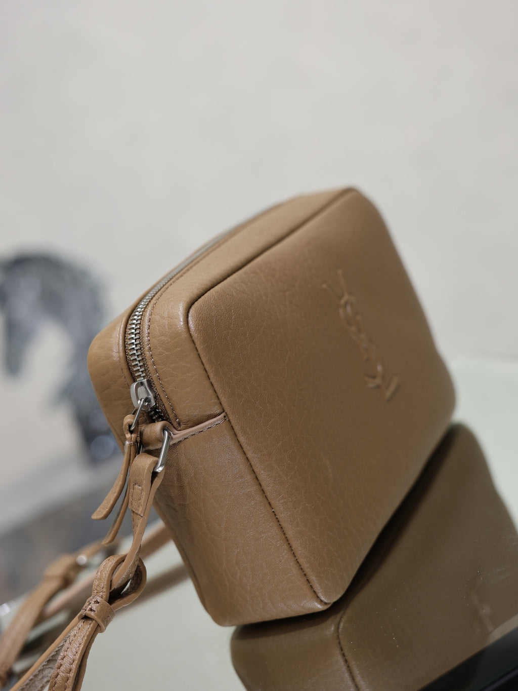 Tan leather YSL crossbody bag with front zipper, angled side view, and logo on flap.