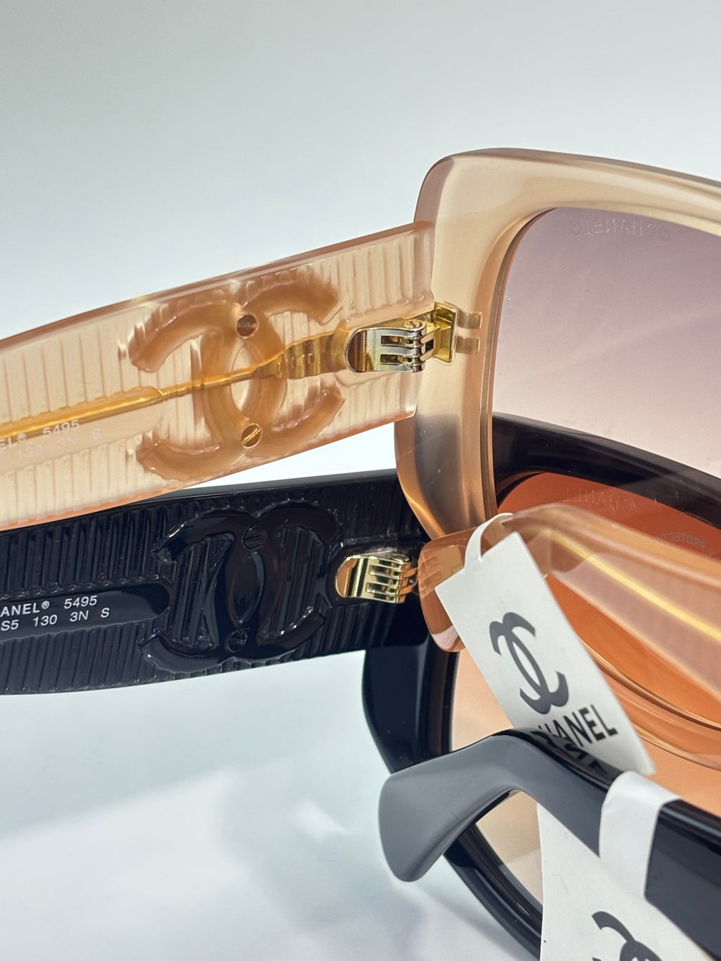 Chanel sunglasses close-up with tan lenses and dark underframe, gold CC branding.