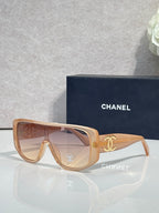 Sunglasses with tan frame and warm brown lenses, gold Chanel CC on temples.