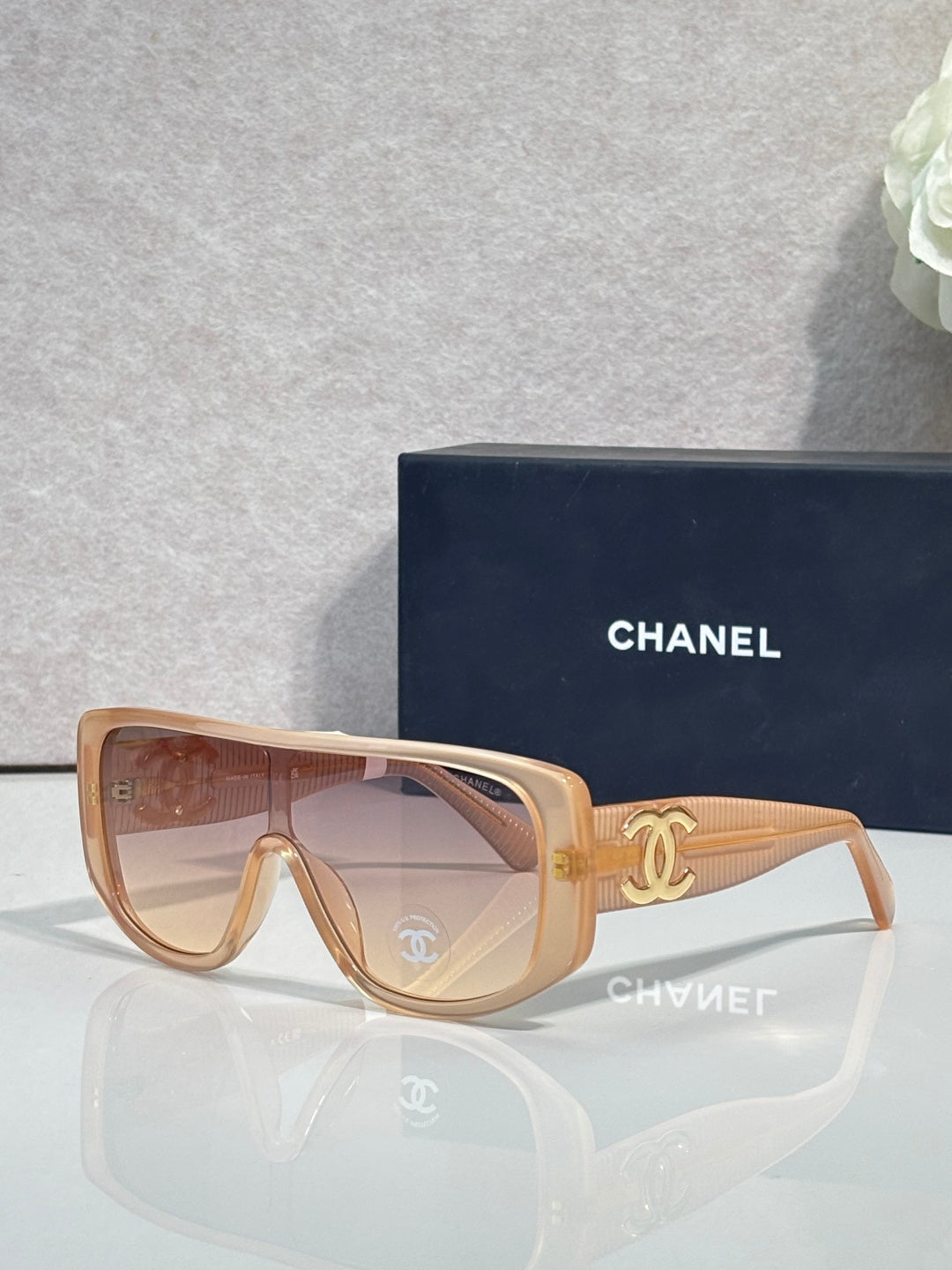 Sunglasses with tan frame and warm brown lenses, gold Chanel CC on temples.