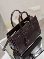Dark brown YSL tote bag with long handles, gold-tone hardware, and front buckles