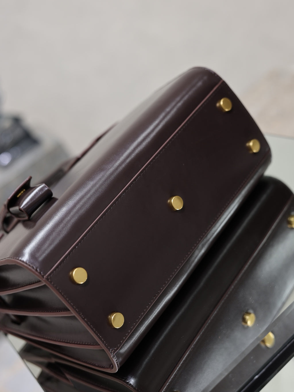 Dark brown YSL tote bag side view with gold snap buttons and leather strap