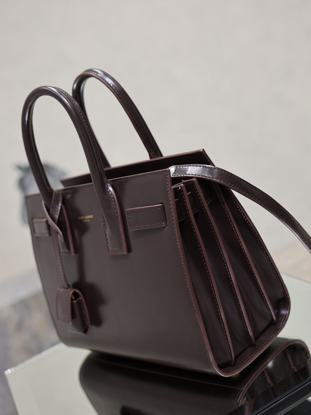 Dark brown YSL structured tote bag with long handles and pleated side panels