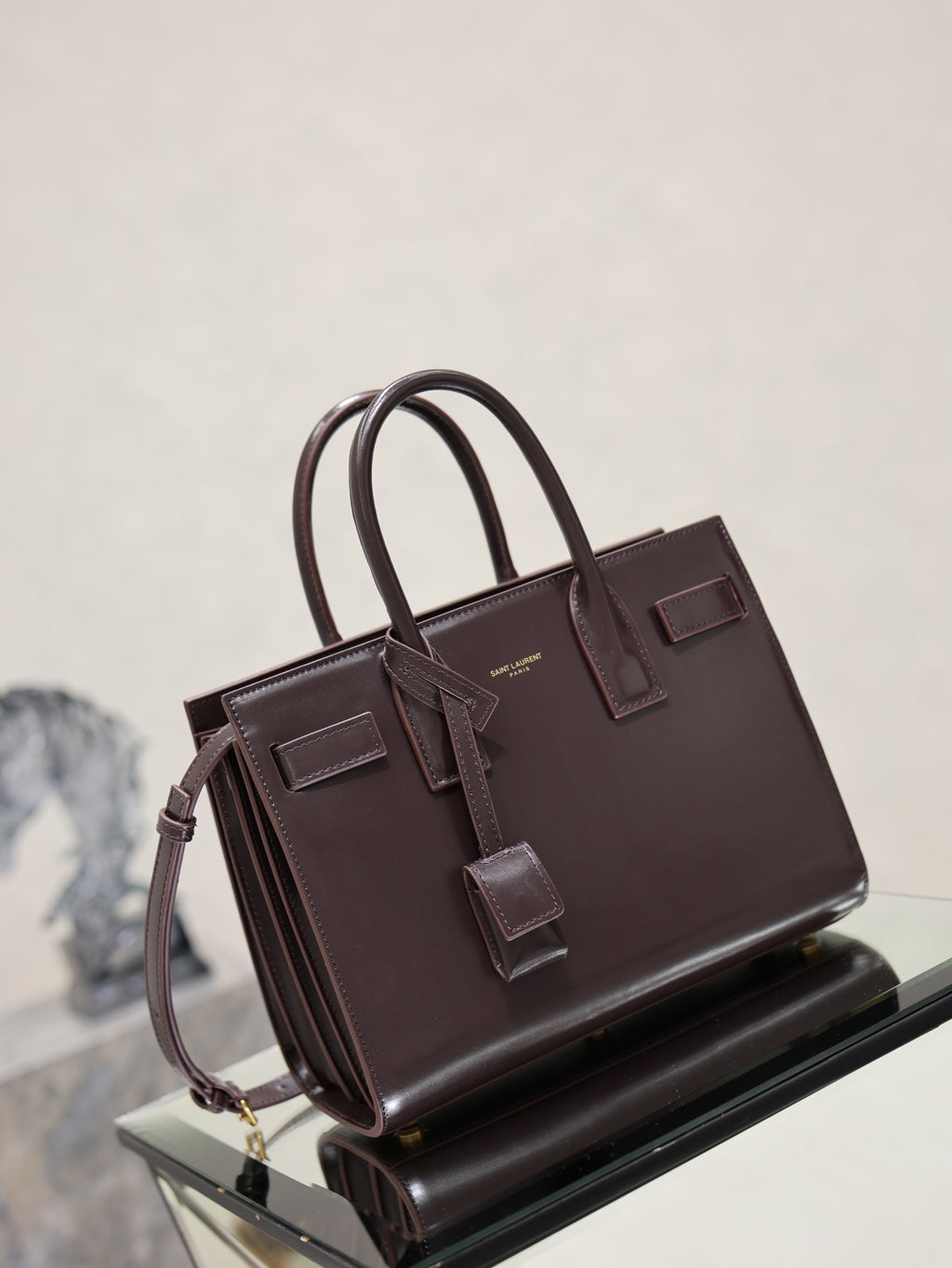 Dark brown YSL tote bag with top handles, front buckled tabs, and strap details