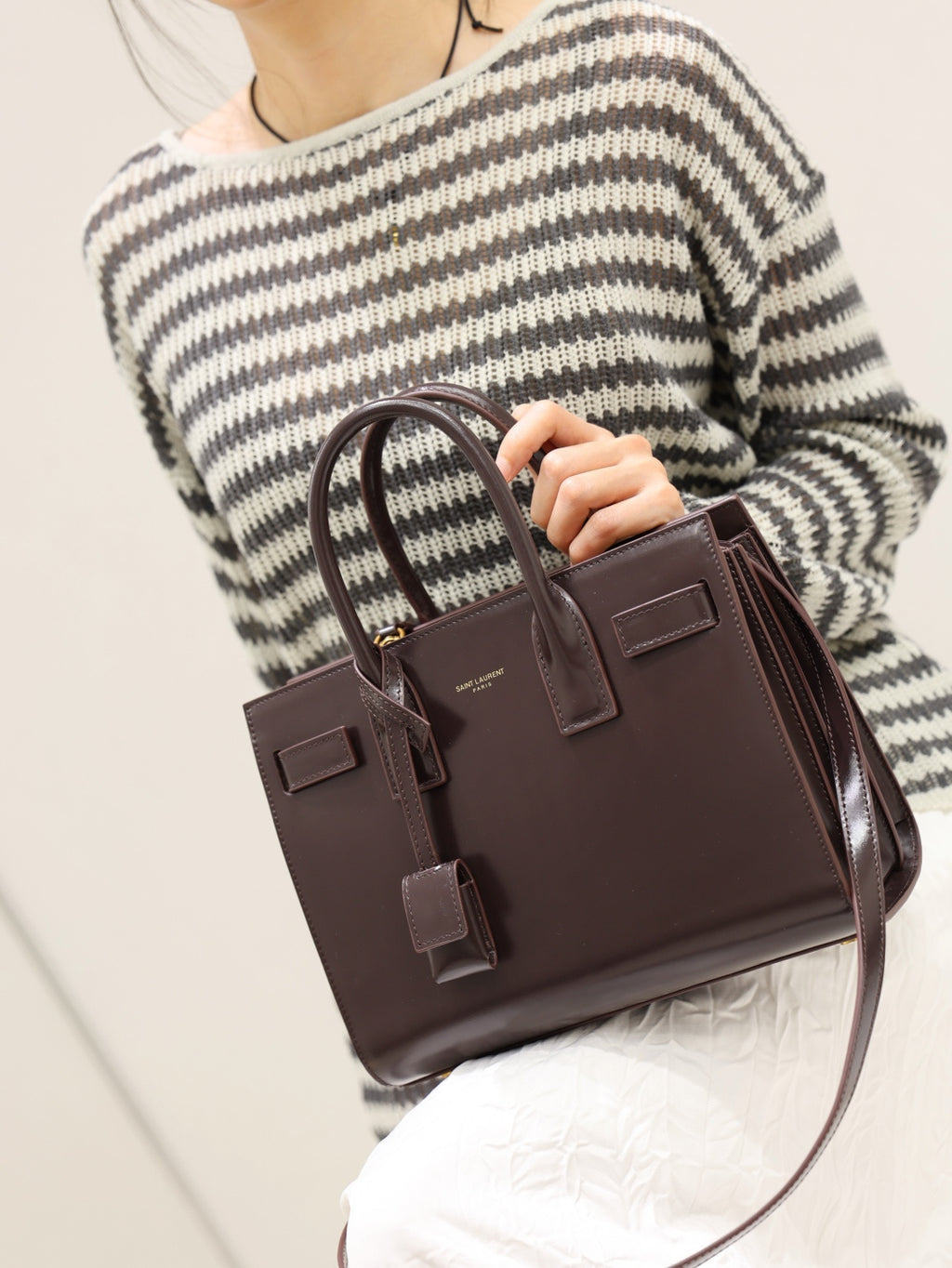 YSL structured leather tote bag with front flap and dangling strap details, dark brown.