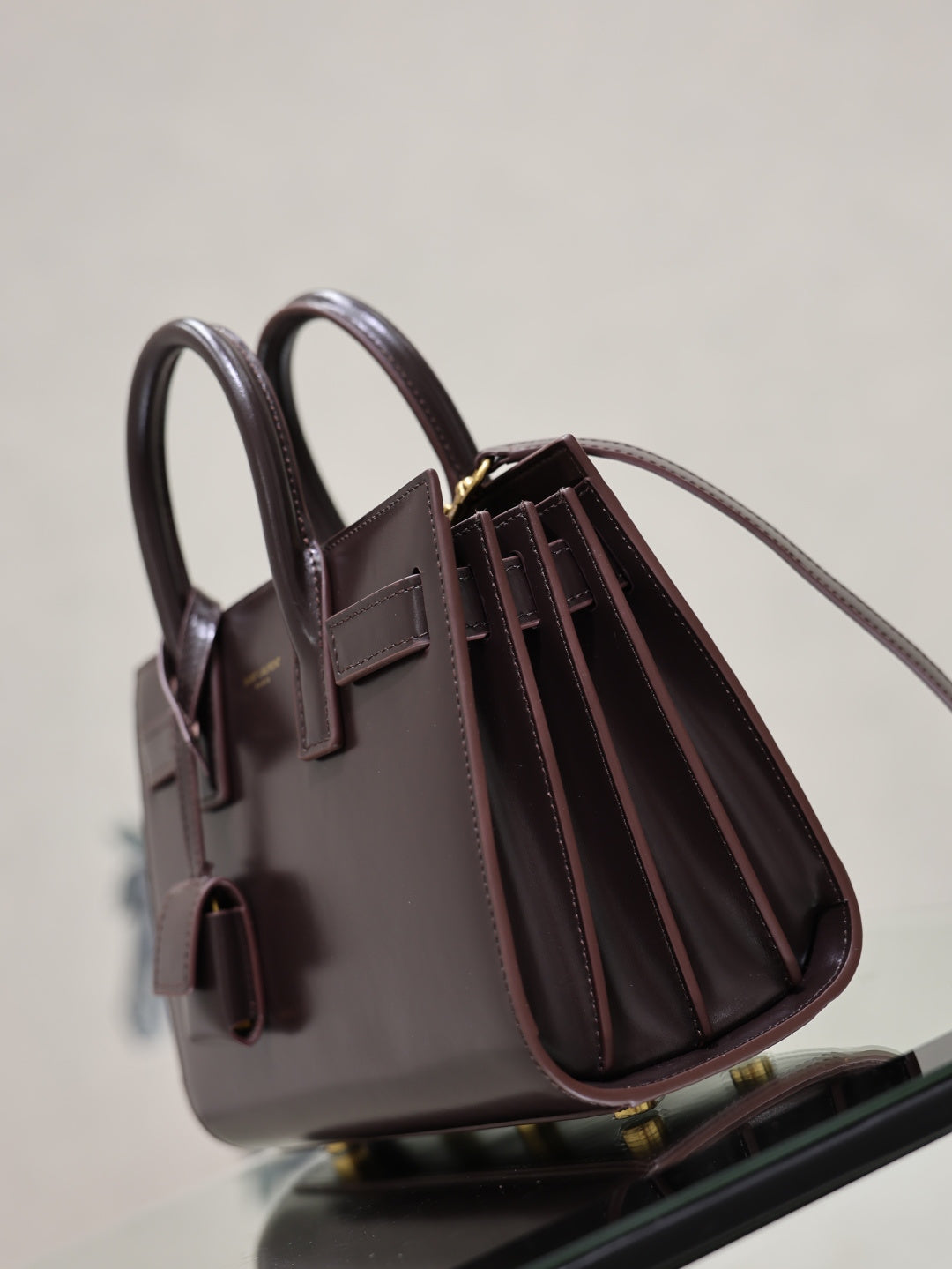 Dark brown leather handbag with double handles and front buckle straps, side angle