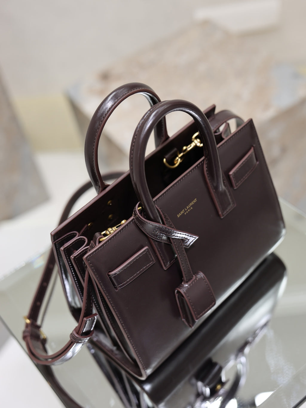 Dark brown leather handbag with double handles, crossbody strap, and gold hardware