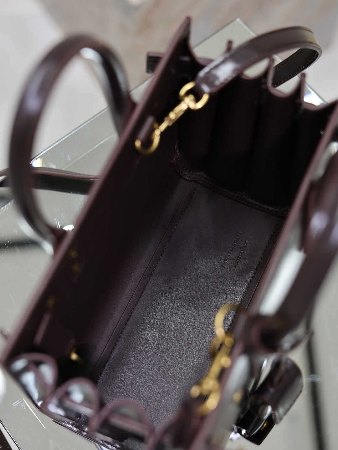 Dark brown leather handbag interior view with gold clasp hardware and top opening