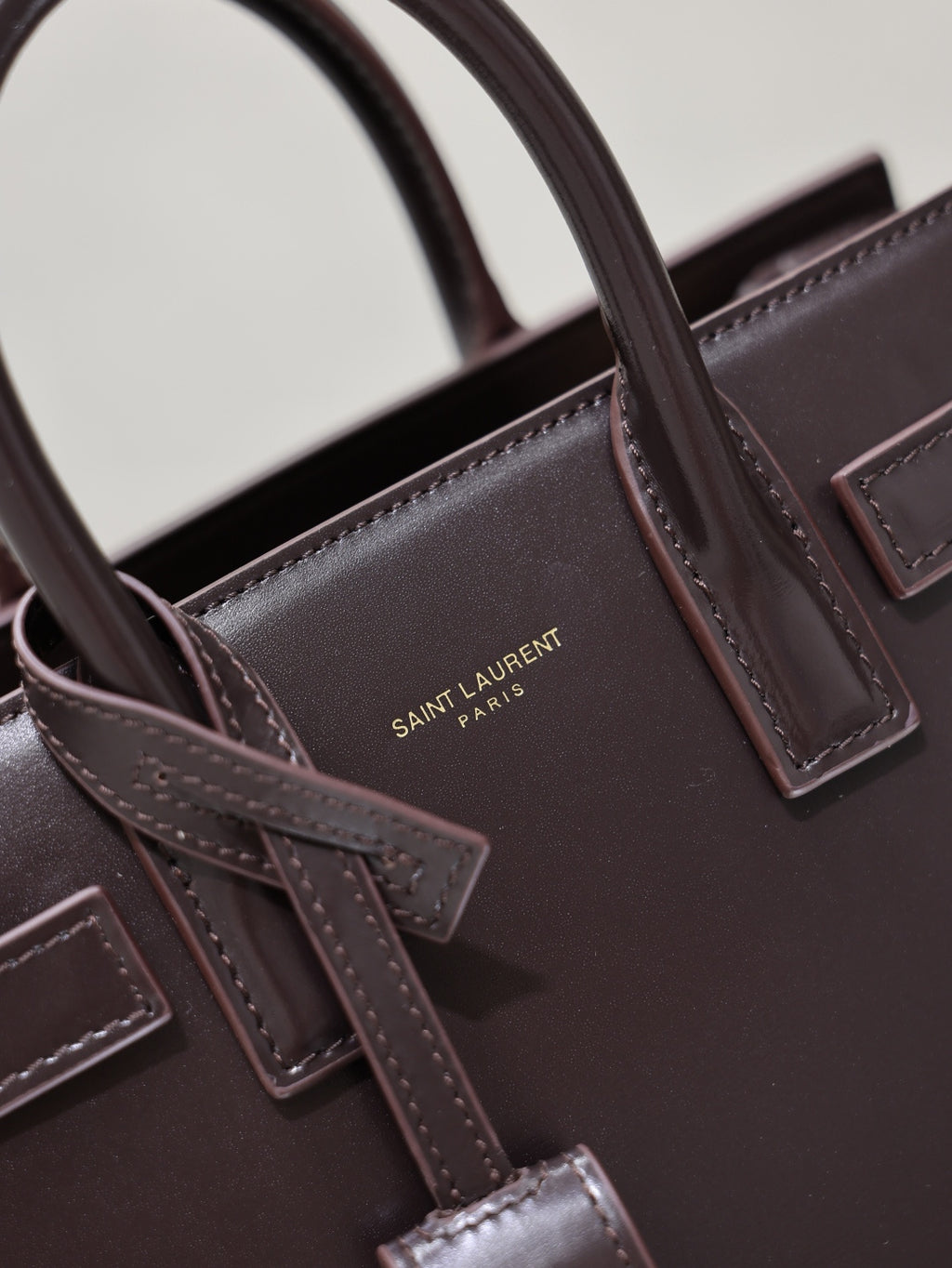 Dark brown leather handbag close-up of front hardware and stitched strap details
