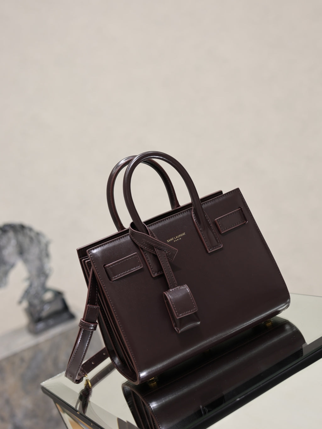 Dark brown leather handbag with double handles, front buckle straps, and side view