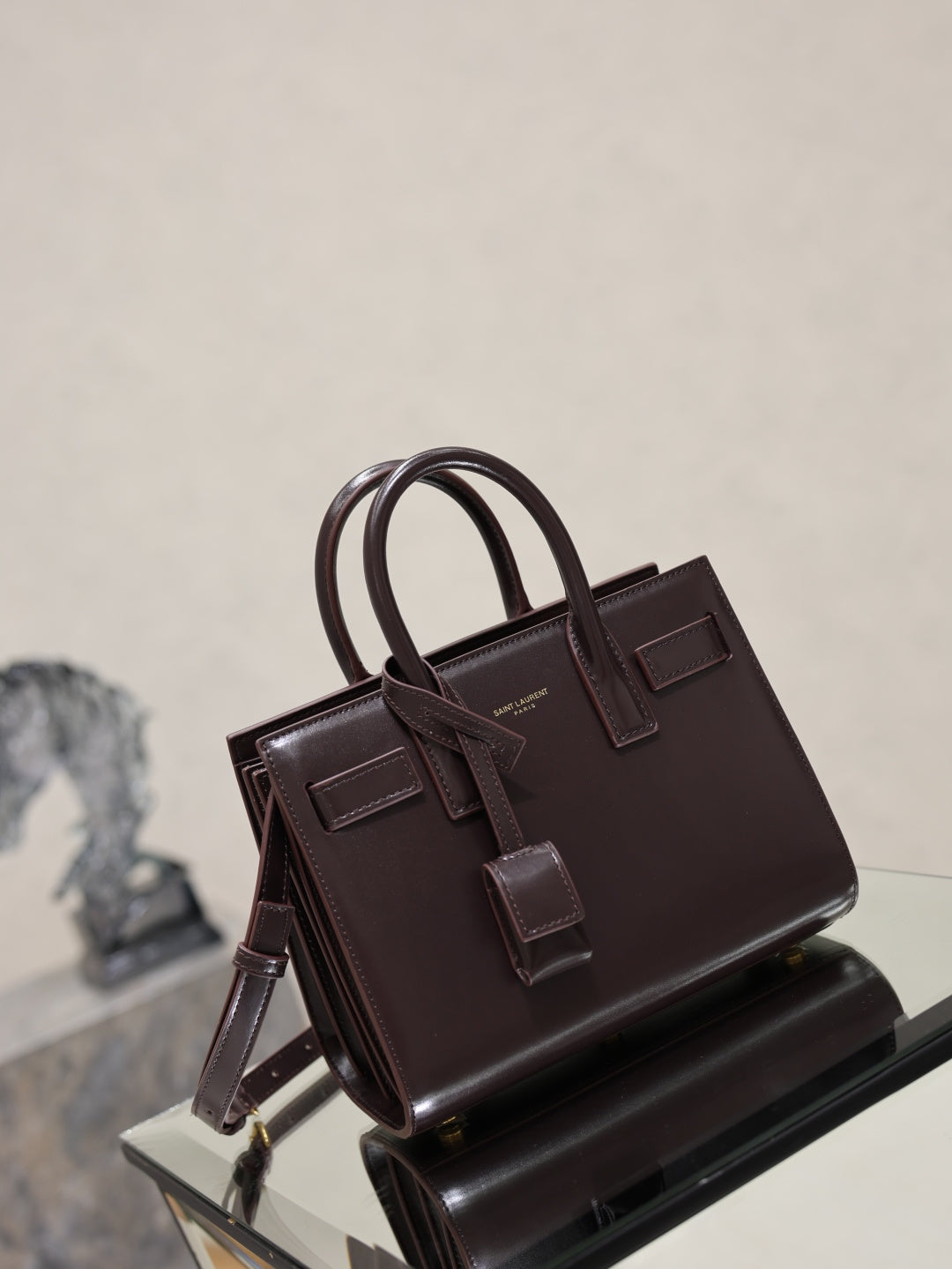 Dark brown leather handbag with double handles, front buckle straps, and side view