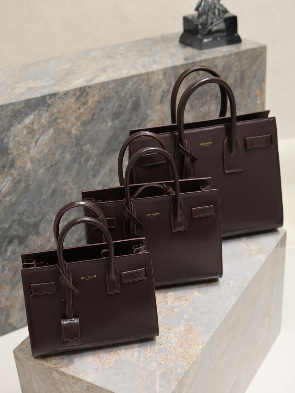 YSL leather tote bag with front buckle detail and top handles, dark brown.