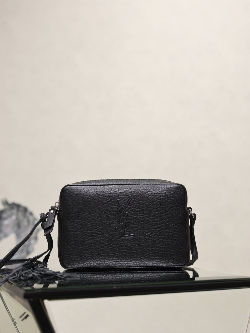 YSL leather crossbody bag, black pebbled texture with front YSL logo and top zip.