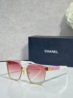 Gold-tone eyeglasses with clear lenses, pink top bar, and magenta temple details