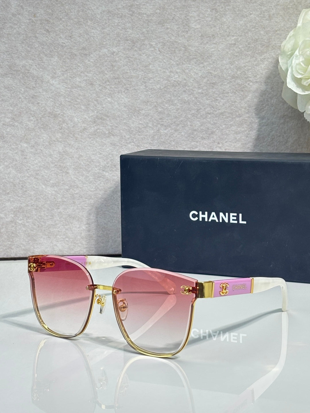 Gold-tone eyeglasses with clear lenses, pink top bar, and magenta temple details