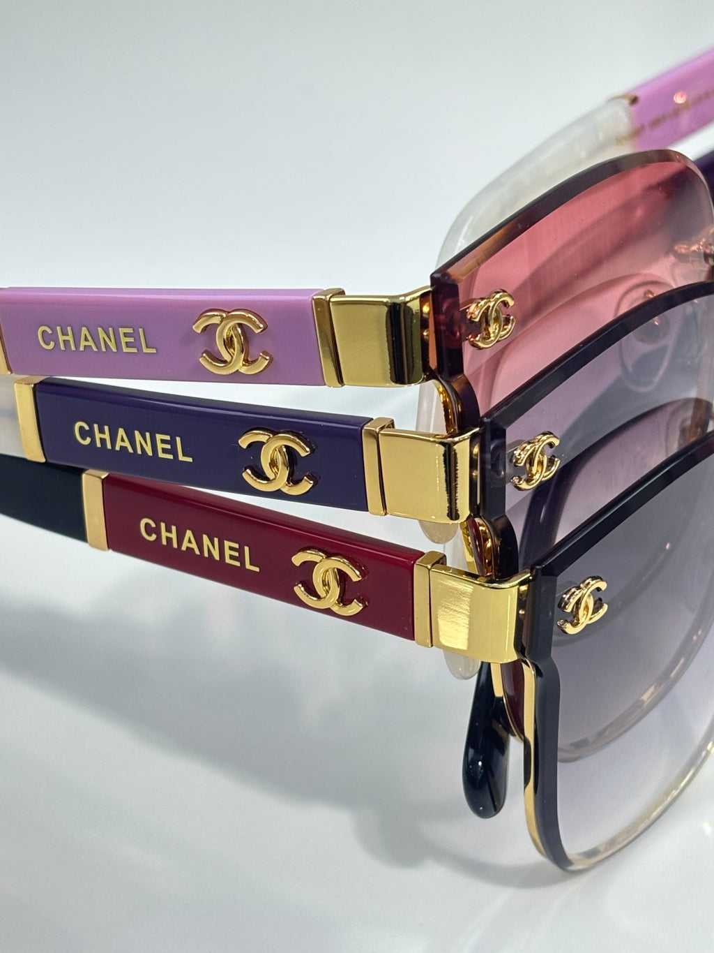 Gold-tone eyeglass frame with stacked logo bands and pink tinted lenses
