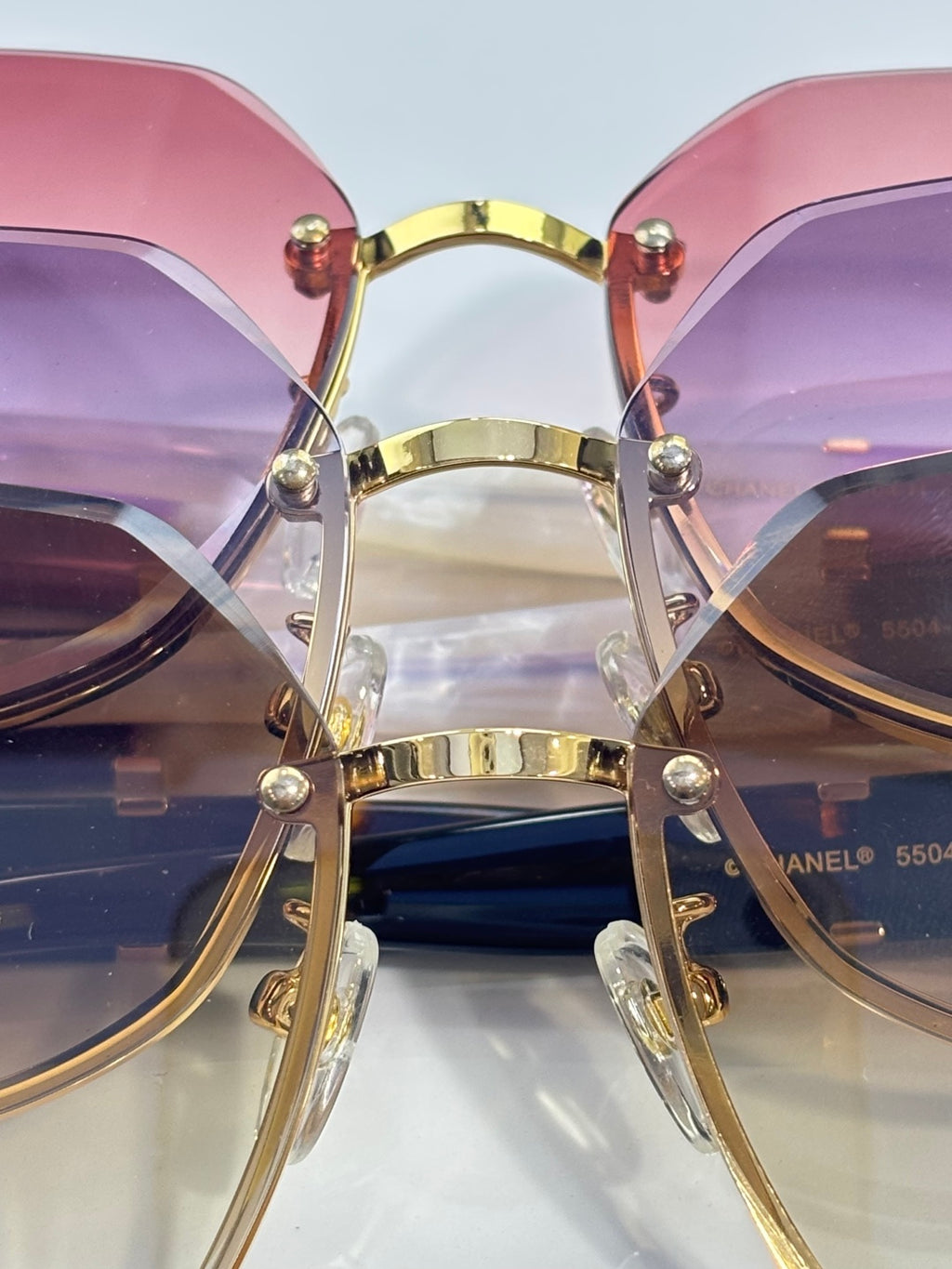 Chanel sunglasses close-up with pink and purple gradient lenses and gold-tone bar bridge