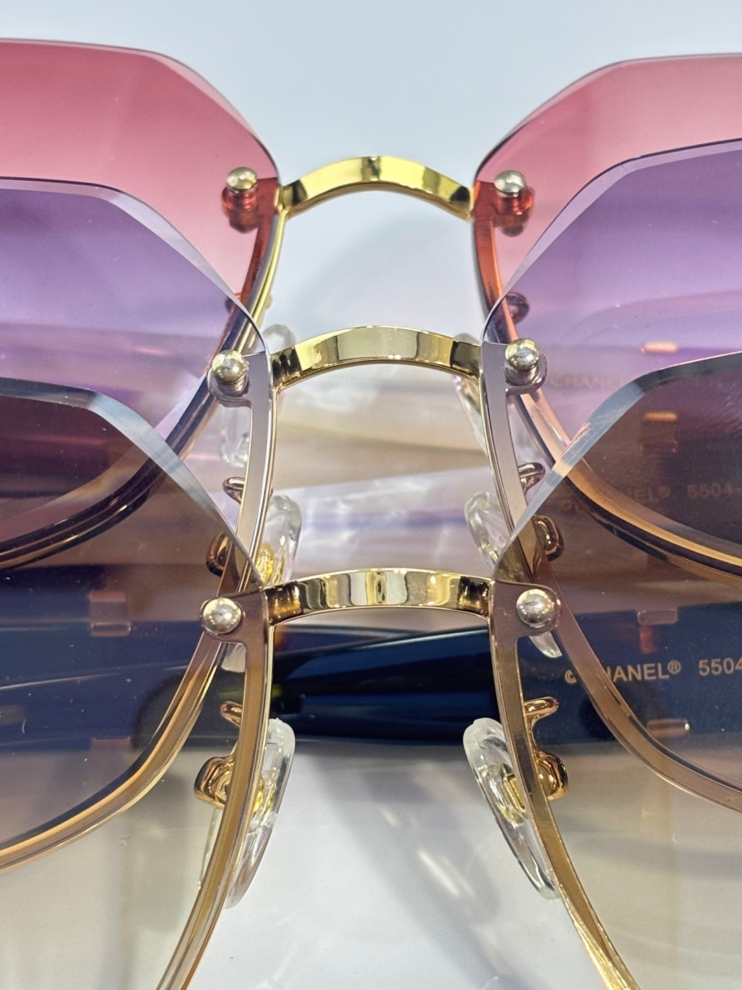 Chanel sunglasses close-up with pink and purple gradient lenses and gold-tone bar bridge
